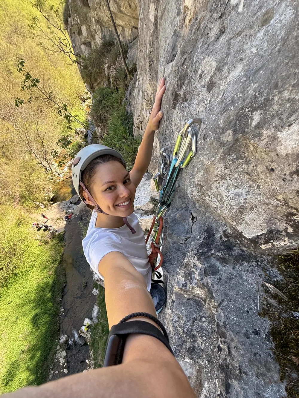 Lora turns to the camera while climbing a rock face