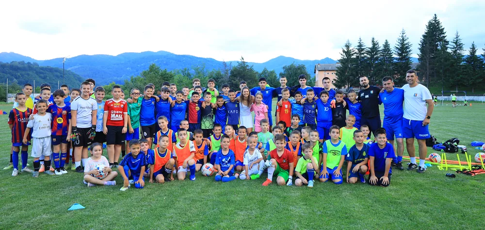 Lora Hristova among the children of the football school on the pitch, the mountains behind