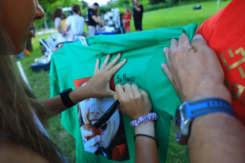 Hands signing a shirt as a keepsake